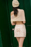 Woman wearing a beige embroidered skirt and shawl against a green door.
