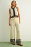 Woman wearing a sleeveless top and wide-leg pants with black stripes on a white background