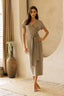 Woman wearing a gray wrap dress in a room with neutral decor