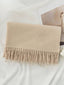 Beige scarf with fringes on a white surface