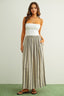 Woman wearing a white strapless top and striped long skirt on a plain background