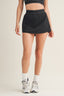 Person wearing a black athletic skirt on a plain background