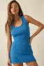Woman wearing a blue crochet dress against a plain background