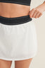 Person wearing a white skirt with black waistband on a beige background