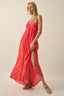 Woman wearing a coral pink dress with a slit on a beige background