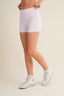 Person wearing white checkered shorts and white sneakers on a beige background