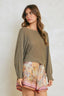 Woman wearing a green sweater and patterned skirt against a plain background