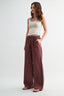 Woman wearing a white tank top and maroon wide-leg pants on a white background