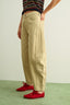 Person wearing beige pants and red shoes on a light green floor.
