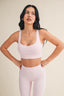 Woman wearing a light pink sports bra and leggings against a beige background