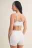 Woman wearing a gray sports bra and white shorts on a beige background