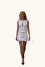 A woman wearing a white sleeveless mini dress with a front zipper and keyhole cutout. 