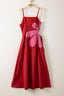 Red dress with pink floral accents on a hanger against a white background