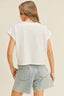 Person wearing a white t-shirt and light blue denim shorts on a beige background
