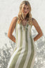 Woman wearing a green and white striped dress against a textured white wall.