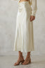 Person wearing a white satin skirt with a plain background
