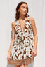 Woman wearing a sleeveless dress with a brown and white floral pattern against a white background