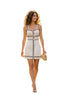 A woman walking outdoors on a stone path wearing a cream-colored sleeveless mini dress with black trim and gold button details, holding a small beige handbag.