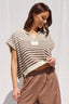 Woman wearing a striped top and brown pants against a white background