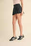 Person wearing a black skirt and Adidas shoes on a beige background
