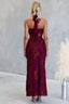 Woman wearing a burgundy lace halter neck dress against a gray background