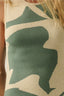 Close-up of a sleeveless top with large green leaf design on beige background