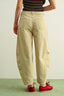 Person wearing beige pants and a striped top on a light green background