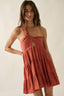Woman wearing a rust-colored dress with cut-out details on a plain background