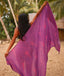 Woman holding a purple scarf with pink leaf pattern in a tropical setting
