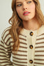 Woman wearing a striped sweater with buttons on a plain background