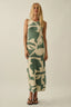 Woman wearing a green and beige patterned dress on a plain background