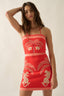 Woman wearing a red dress with white patterns on a plain background