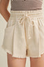 Beige shorts with a drawstring waist on a plain background