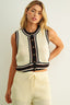 Woman wearing a sleeveless crochet top with buttons and matching pants on a plain background