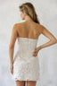 Woman wearing a white lace dress against a plain background