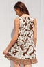 Woman wearing a sleeveless dress with a floral pattern against a white background