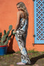 Woman in a floral jumpsuit standing in front of an orange wall with a blue door.