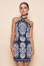 Woman wearing a navy blue dress with white and purple patterns on a beige background