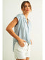 Woman wearing a light blue sleeveless shirt and white shorts on a plain background