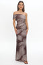 Woman wearing a strapless dress with palm leaf pattern on a white background