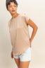 Woman wearing a beige t-shirt and white shorts on a plain background