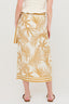 Person wearing a white top and gold leaf patterned skirt on a white background