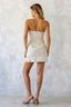 Woman wearing a strapless lace dress against a plain background