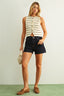 Woman wearing a striped sleeveless top and denim shorts against a plain background