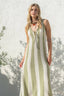 Woman wearing a green and white striped dress against a textured white wall.