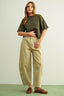 Woman wearing an olive green shirt and beige pants on a light green background