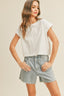 Woman wearing a white top and light blue jeans on a beige background
