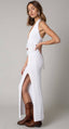 Woman wearing a white dress with a slit and brown boots on a plain background