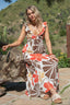 Woman in a floral dress standing outdoors with a scenic background