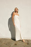 Woman in a white strapless gown standing against a light-colored wall.